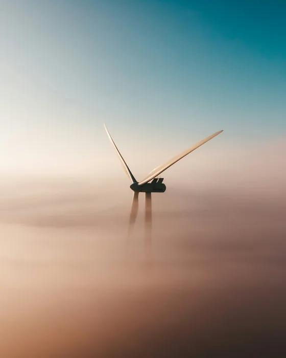 Wind turbine emerging from a sea of clouds