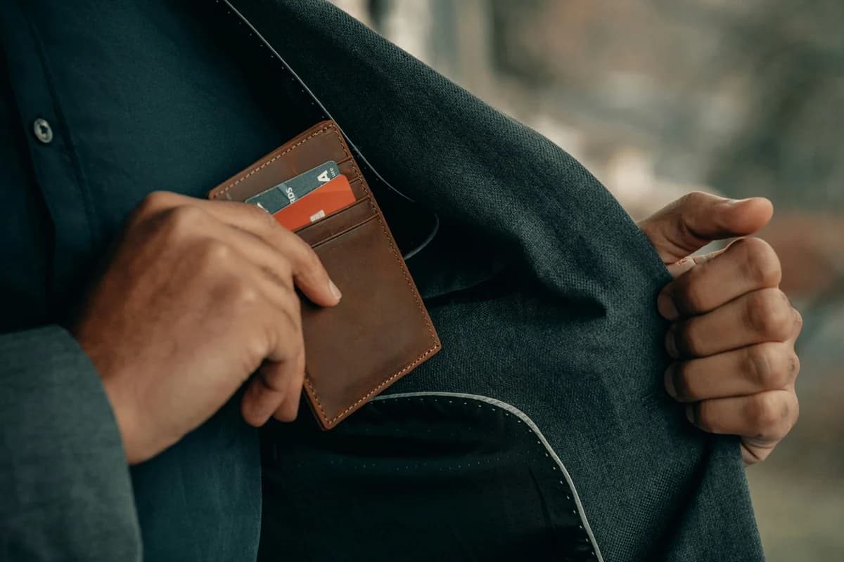 A hand drawing a wallet and bank cards from a jacket