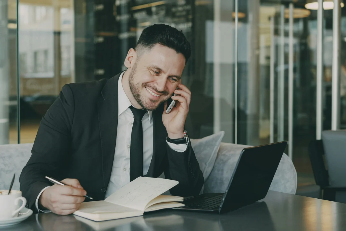 An adviser on the phone in front of a laptop and a notebook