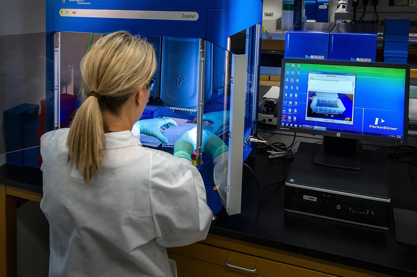 Technicienne de laboratoire devant un automate de préparation d'échantillons